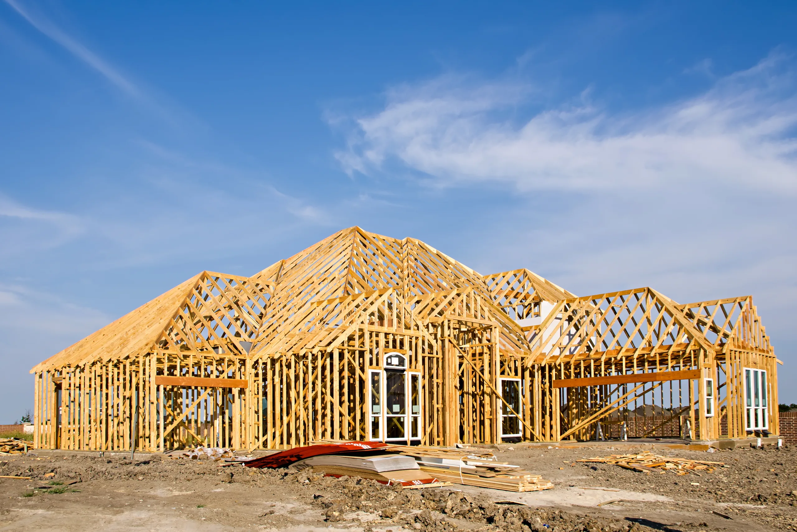 New residential home under construction with wooden framing against a blue sky.